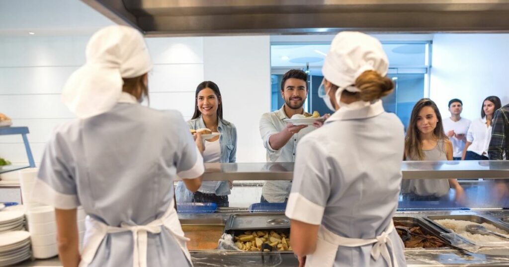 Customers at a buffet restaurant receiving their plates from the kitchen assistants looking very happy