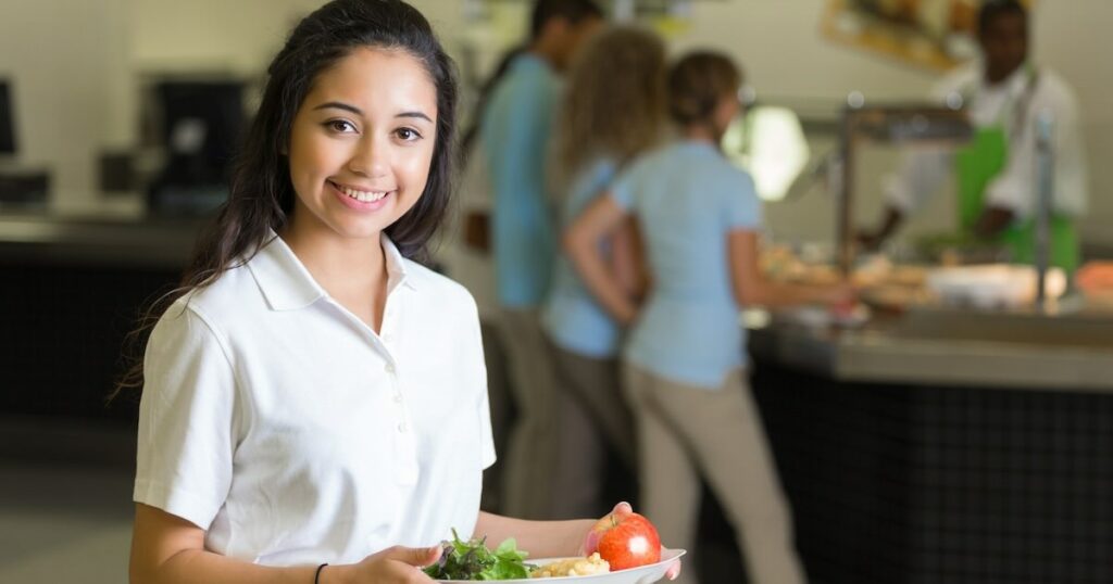 High school student holding healthy lunch in cafeteria